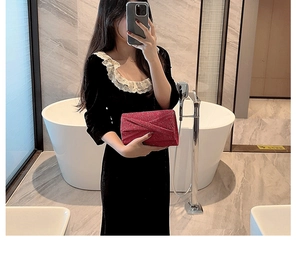 Détail d'une pochette rouge à paillettes plissée tenue par un modèle en robe de velours