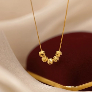 Golden five-bead lucky charm necklace displayed on luxury red velvet and silk fabric