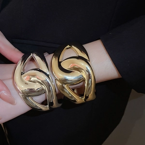 Close-up of chunky intertwined metal chain bracelets in gold and silver finish