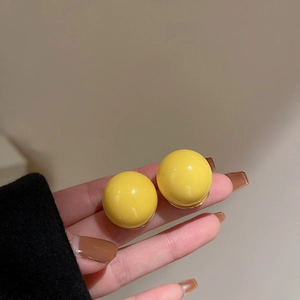 Nahaufnahme gelber runder Ohrstecker, von Hand vor weichem Hintergrund präsentiert