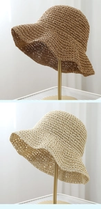 Close-up detail of woven straw sun hats in tan and beige showing fine texture