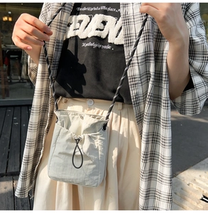 Close-up of a light grey drawstring crossbody bag for sports and outdoor bottle storage
