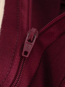 Close-up of a high-quality dark red YKK zipper on vintage American jacket fabric