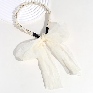 Detail of white mesh bow headband with elegant pearls and gold beads on a metal frame