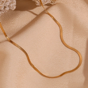 Close-up of a 2mm gold-plated stainless steel snake chain on champagne textured fabric