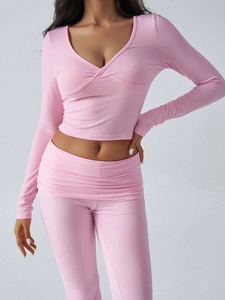 Detail of pink knitted set with criss-cross neckline top and high-waisted pleated pants