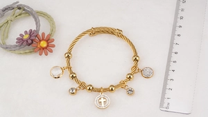 Close-up of gold 18K plated stainless steel cross charm bracelet with size ruler reference