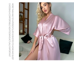 Détail de la texture du peignoir en satin rose et col en V avec ceinture en soie assortie