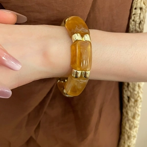 Detail of amber resin beaded bracelet with gold metal accents on model wrist