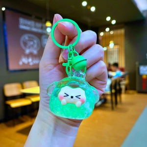 Close-up of a green jelly lamb keychain with a cute face, bell, and matching hook