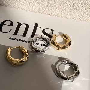 Boucles d'oreilles créoles dorées et argentées à texture froissée sur un magazine chic