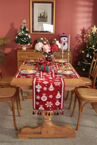 Detail of red Christmas table runner with snowflake patterns and festive tassels on wood