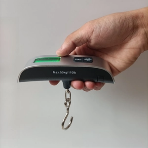 Close-up of portable luggage scale with green backlit LCD display and 50kg capacity