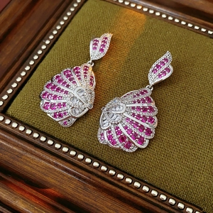 Detailed close-up of fan-shaped vintage earrings with purple stones on green velvet