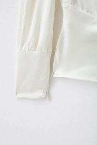 Vue détaillée des poignets d'une chemise en satin blanc avec fermeture éclair latérale