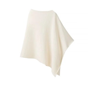 Close-up of white knit poncho featuring irregular cut and premium textured fabric detail