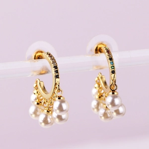 Detailed shot of golden hoop earrings with colorful gemstones and hanging white pearls