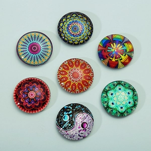 Set of seven glass mandala and yin yang pattern refrigerator magnets on blue surface