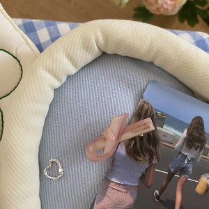 Detailed view of a pink acetate knot hair clip with Handmade text on a soft blue fabric