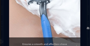 Detail showing a blue and black manual razor gliding through thick white shaving foam on skin