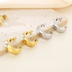 Detailed view of gold and silver C-shaped stainless steel earrings with sparkling zircon