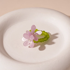 Macro detail of sweet floral beaded ring featuring purple resin petals and green matte beads