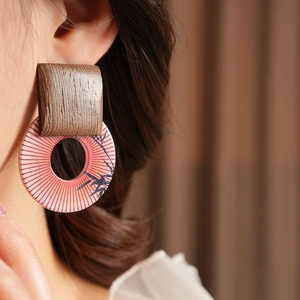 Close-up of geometric earrings with wood texture and bamboo pattern on a model