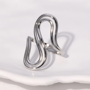 Minimalist silver S-shaped wavy stainless steel open ring on a clean white textured background