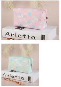 Close-up of quilted PVC makeup bags in pink and mint green with heart pattern
