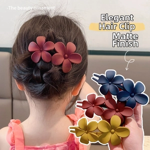 Detail of matte flower hair clips in burgundy, navy, and yellow for elegant hairstyling