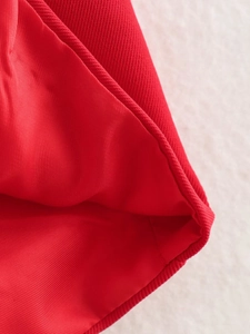 Detailed view of red twill fabric stitching and hem finish on a halter top
