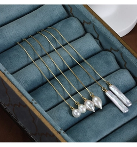Detail of three Baroque freshwater pearl drop earrings on golden box chains in velvet