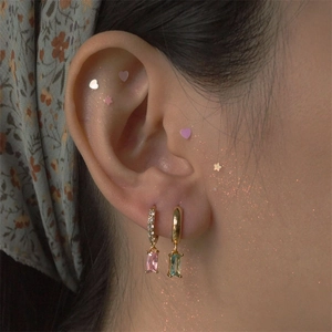 Close-up of gold earrings featuring rectangular pink and light blue gemstone pendants