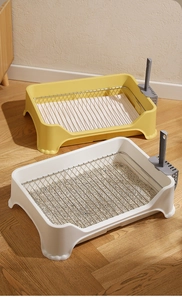 Detail of open dog potty with stainless steel mesh tray and matching scooper on wood floor