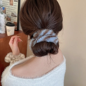 Dettaglio di elastico per capelli in peluche a righe blu e marroni su uno chignon