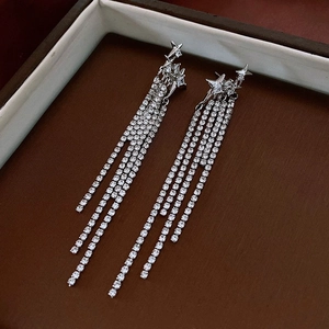 Detail of silver long tassel earrings with star elements and shimmering rhinestones