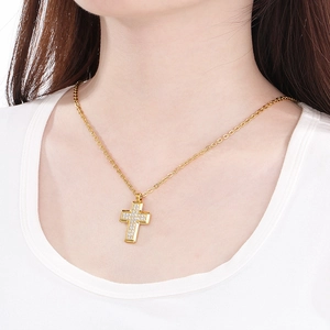 Close-up of golden cross necklace with inlaid zircons worn by model on white tee