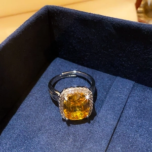 Detailed macro view of yellow oval gemstone ring with pavé diamond halo in blue velvet box