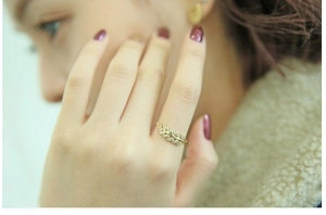 Detailed view of a gold leaf-shaped ring encrusted with shimmering cubic zirconia stones