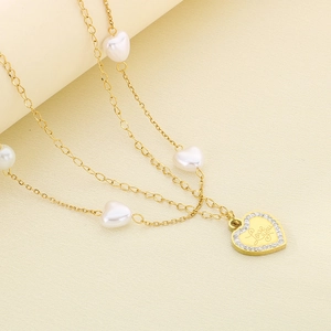 Macro shot of gold layered necklace featuring heart pearls and Love you engraved pendant