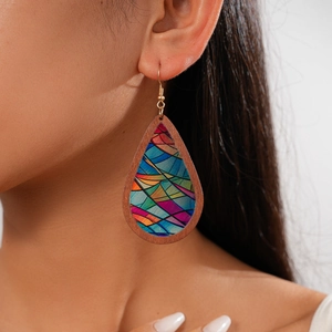 Detail of bohemian wood teardrop earring with geometric patterns worn by a model
