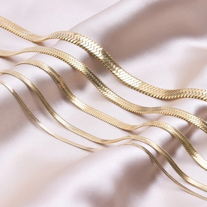 Flat 18k gold snake chain necklace and bracelet in five various widths on champagne silk