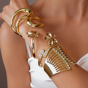 Detail von goldenen geometrischen Armreifen mit funkelnden Strasssteinen am Arm