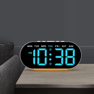 Detalle de reloj digital LED ovalado con pantalla azul e iluminación ambiental naranja cálida