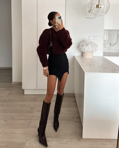 Détail d'un pull en maille duveteuse bordeaux avec jupe noire fendue et bottes hautes
