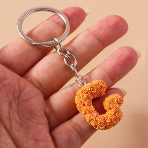 Detailed view of a silver keychain with letter G made of tiny orange resin roses