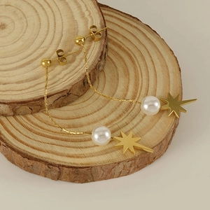 Elegant gold starburst earrings with pearl accents displayed on minimalist wooden stands