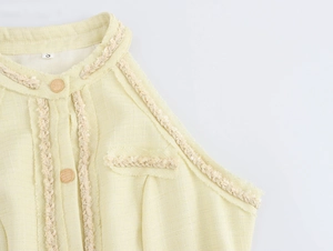 Détail de la robe sans manches en tweed jaune avec boutons dorés et franges
