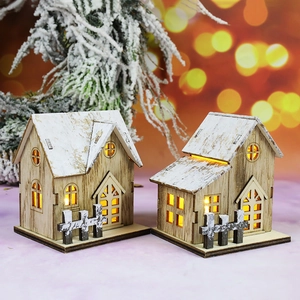 Detail of two wooden Christmas house ornaments with warm LED light and snow-capped roofs