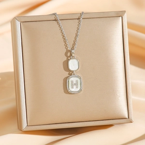 Elegant silver H-letter square shell pendant necklace with diamonds on silk background